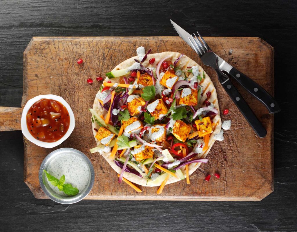Paneer loaded naan with tomato salsa and yogurt and mint to the left